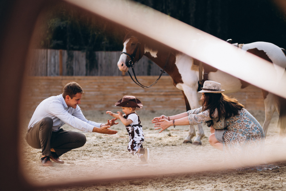 little boy learns to walk. parents and horse nearby